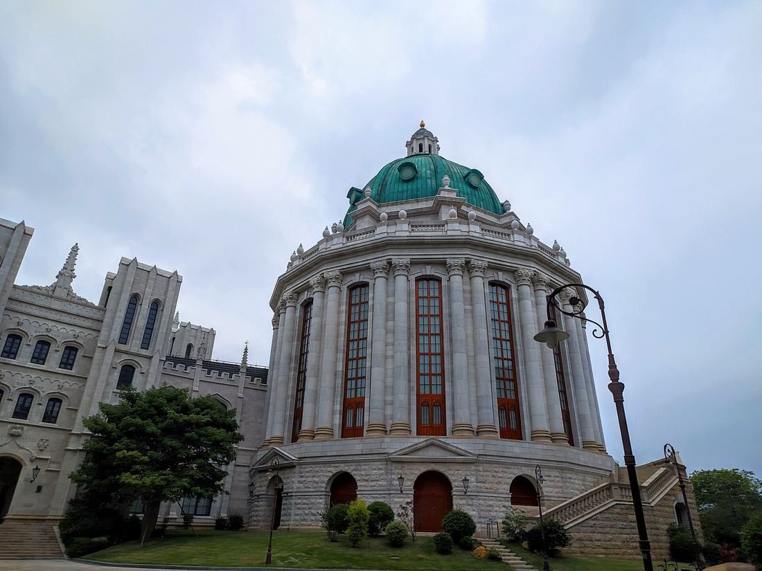 Huawei: Domed rotunda with tall arched windows next to a stone Gothic-style wing