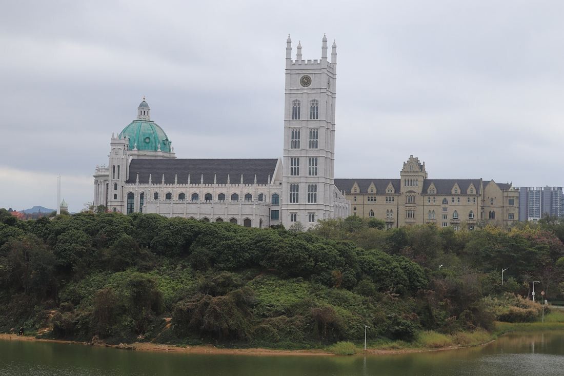 Huawei: Gothic-style tower and domed hall above a wooded lakeshore