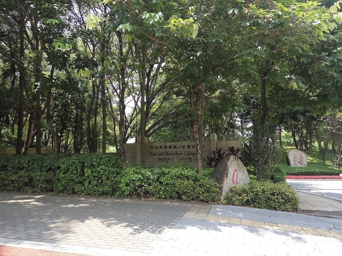 Huawei: Leafy entrance with trees, hedges and a stone marker