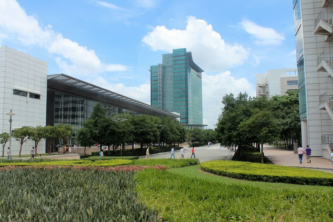 Huawei: Low glass-fronted building and a green glass tower behind flower beds and lawns