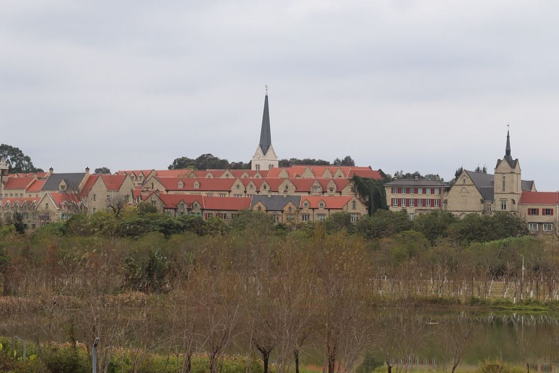 Huawei: Row of red-roofed European-style buildings and a spire across reeds