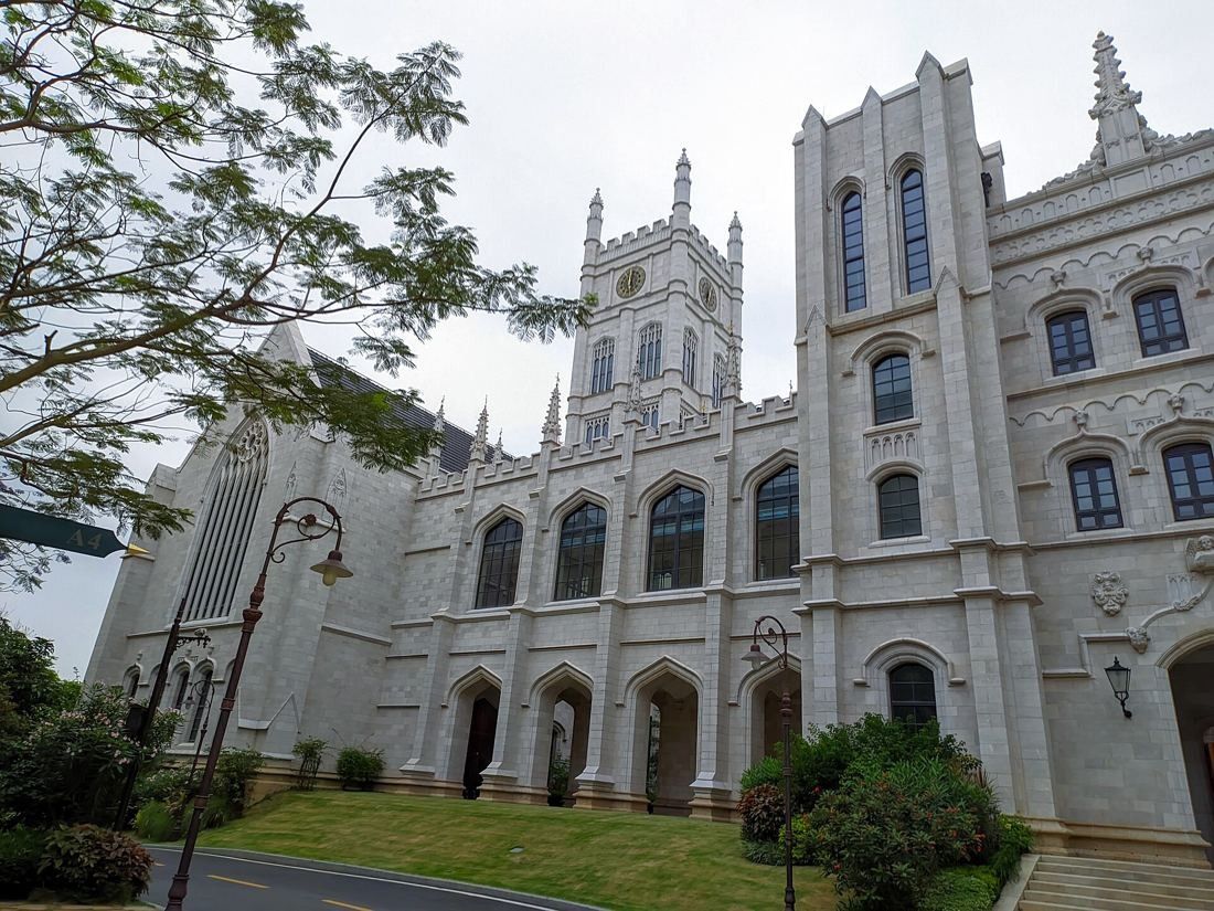 Huawei: White Gothic-style facade with pointed windows and turrets behind a lawn