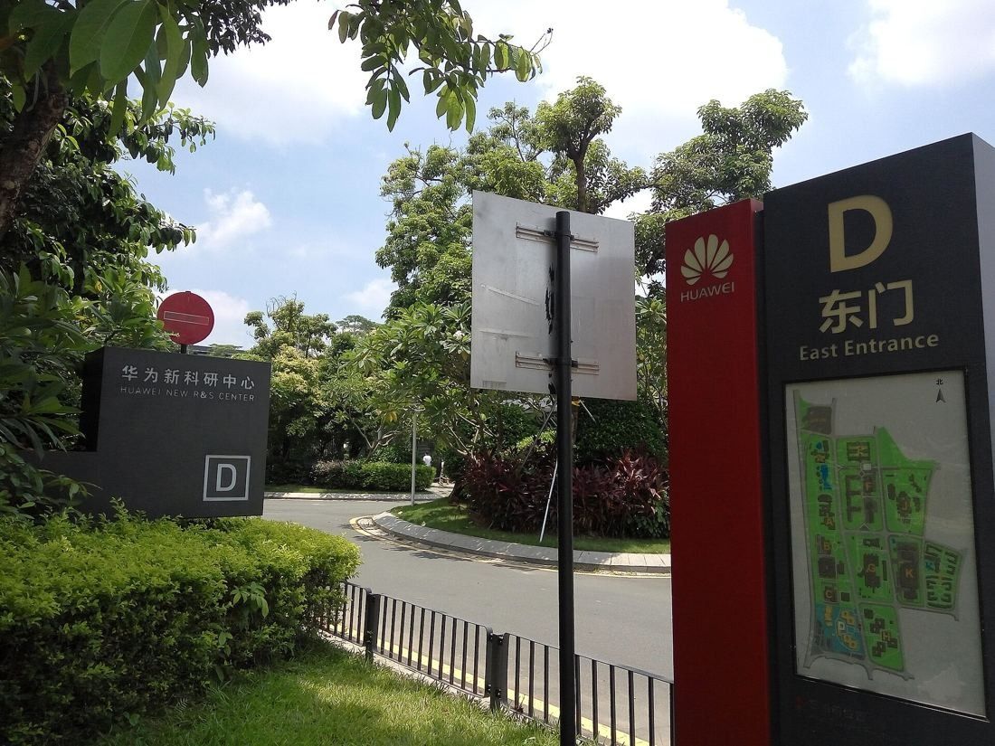 Huawei: Zone D east entrance sign with a campus map among trees