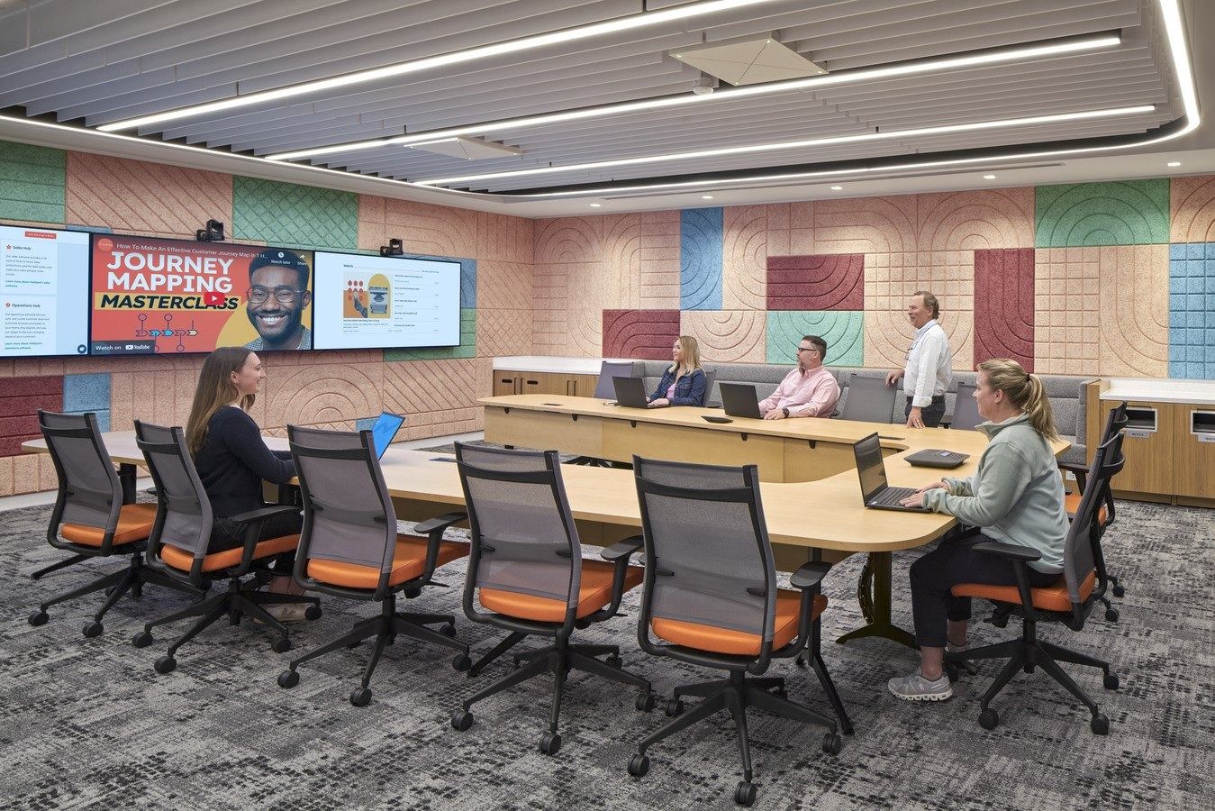 HubSpot: A long meeting table before a pastel tile wall