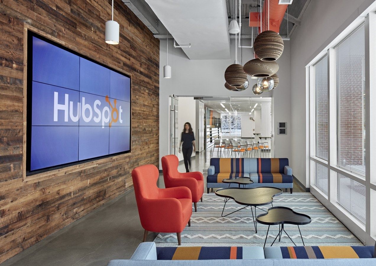 HubSpot: A lounge with red chairs below a big HubSpot screen