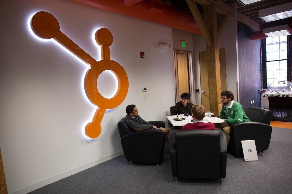 HubSpot: A meeting nook beside a glowing HubSpot sprocket logo