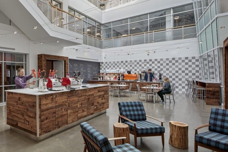 A skylit atrium with a reclaimed-wood bar and plaid armchairs