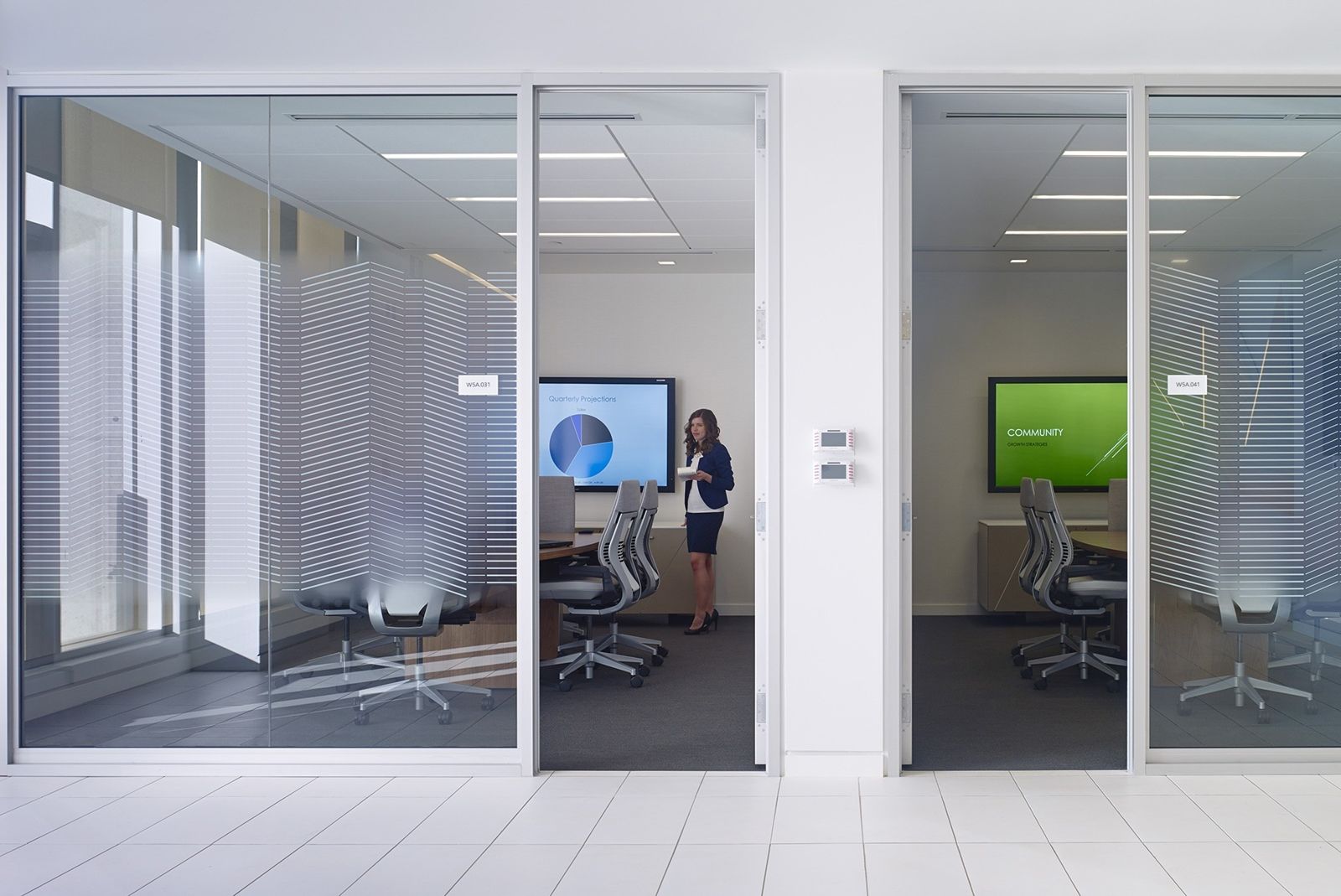 Imperial Oil: Glass-walled meeting rooms with screens along a white corridor