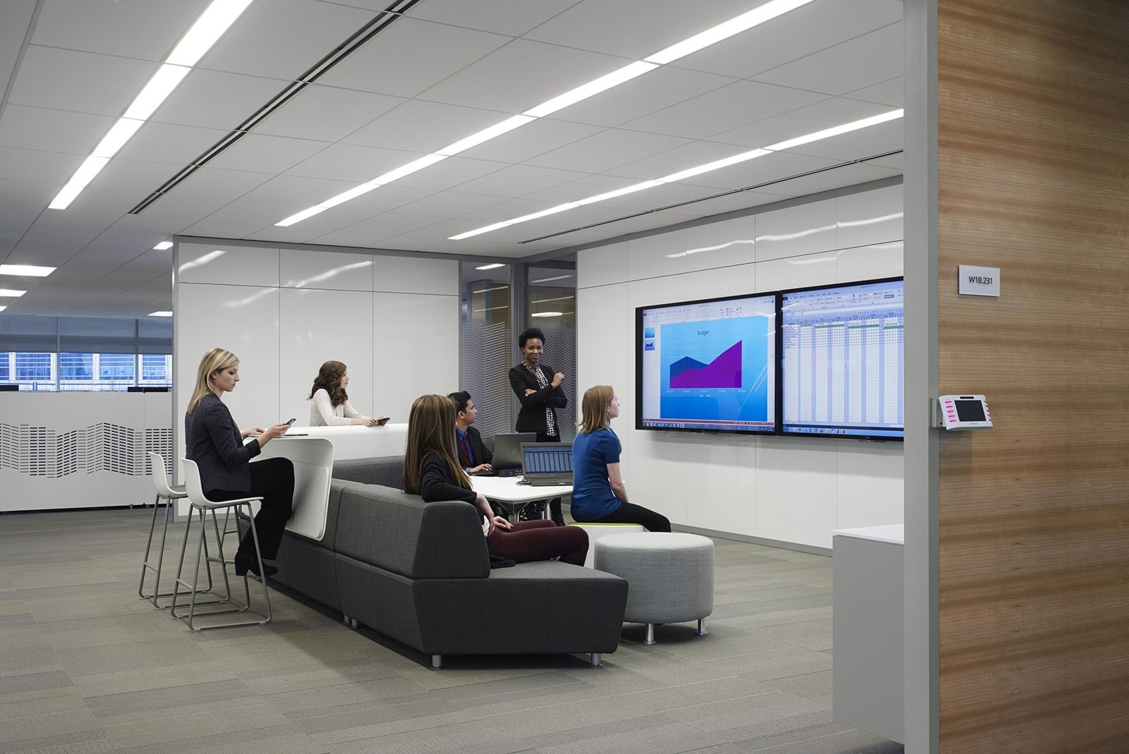 Imperial Oil: People meeting on sofas and stools in front of large wall screens showing charts