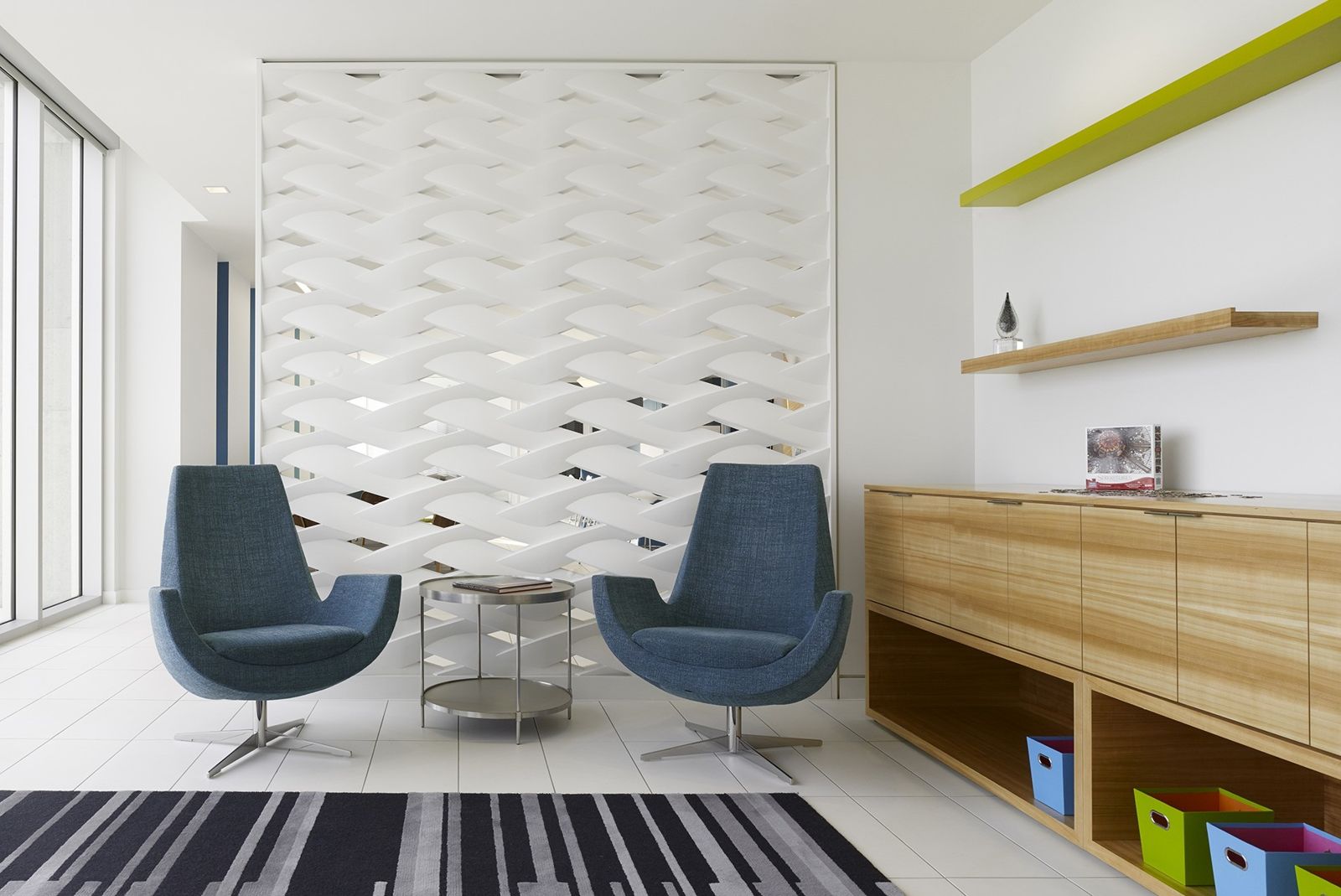 Imperial Oil: Two blue armchairs in front of a white sculpted wall panel and timber cabinets