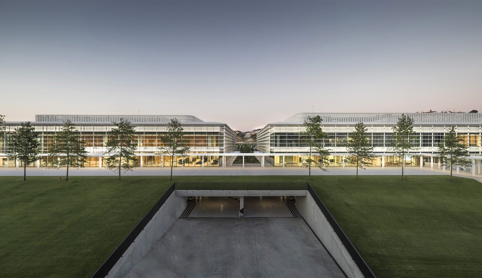Inditex: Courtyard lawn between low glass buildings at dusk