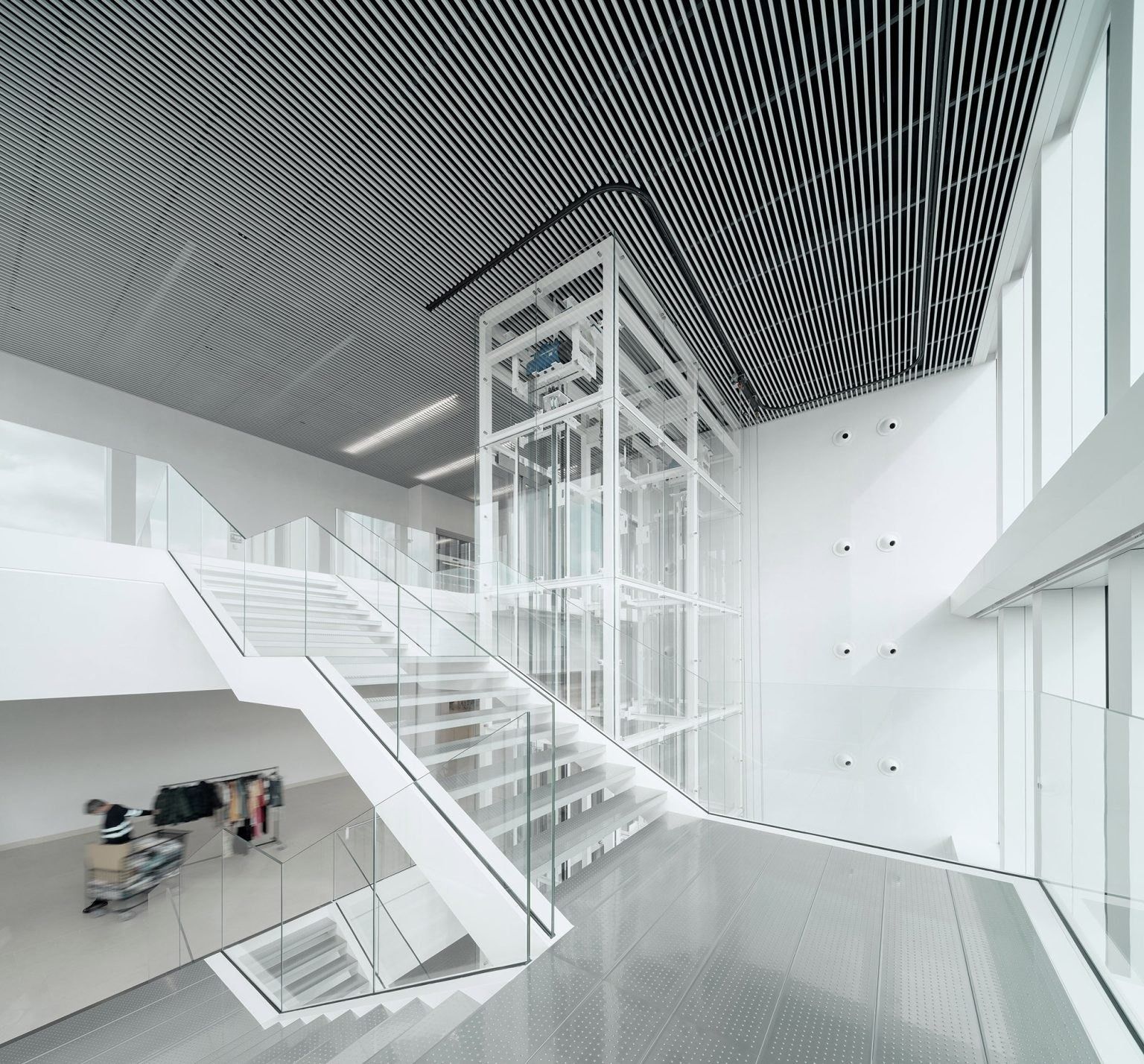 Inditex: White steel stair rising through a double-height space