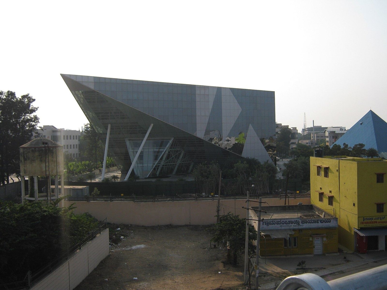 Infosys: Angular dark glass building with a small blue pyramid behind it