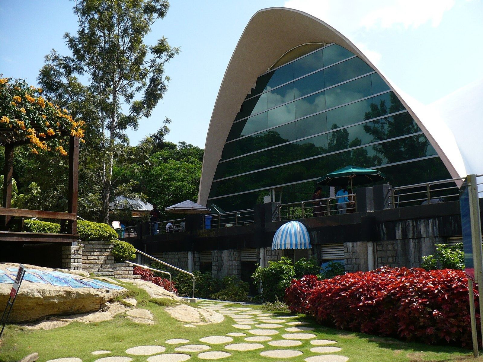 Infosys: Curved glass building with a white arched roof behind a garden