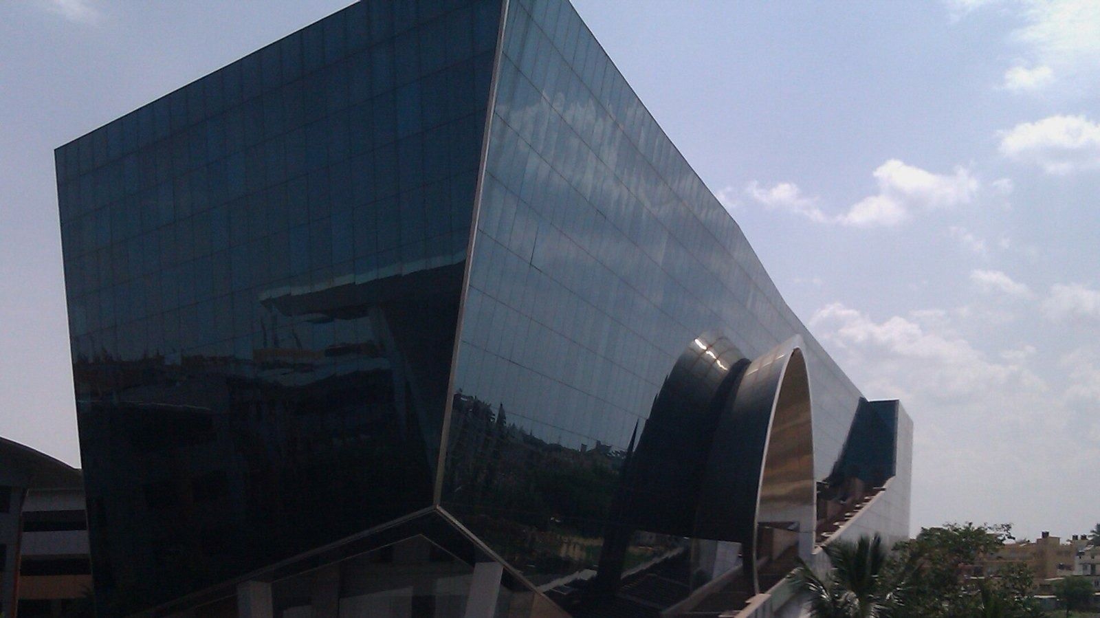 Infosys: Dark glass building with sloping walls and curved openings