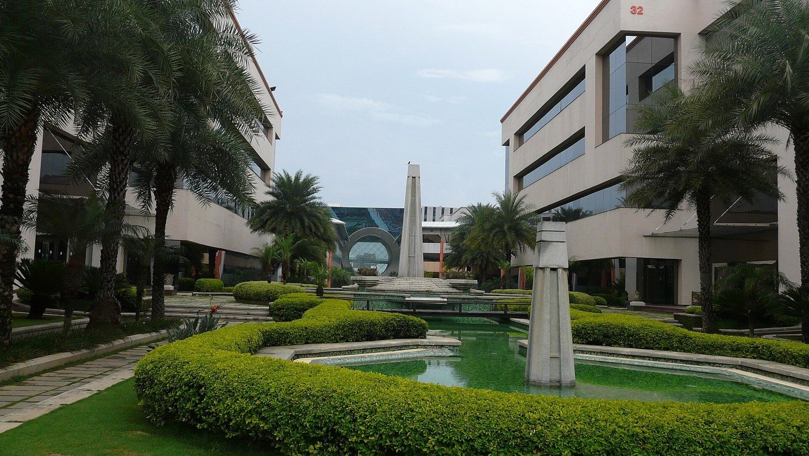 Infosys: Fountain and hedges between office buildings with palm trees