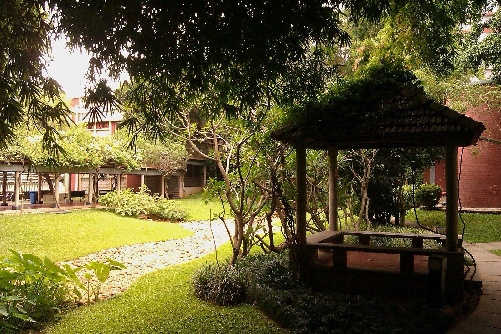 Infosys: Garden with a thatched gazebo and a stone path