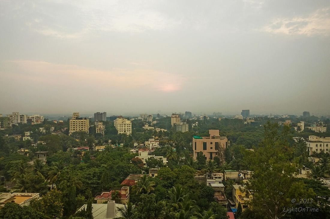 View over low-rise apartment buildings and trees under a hazy sky