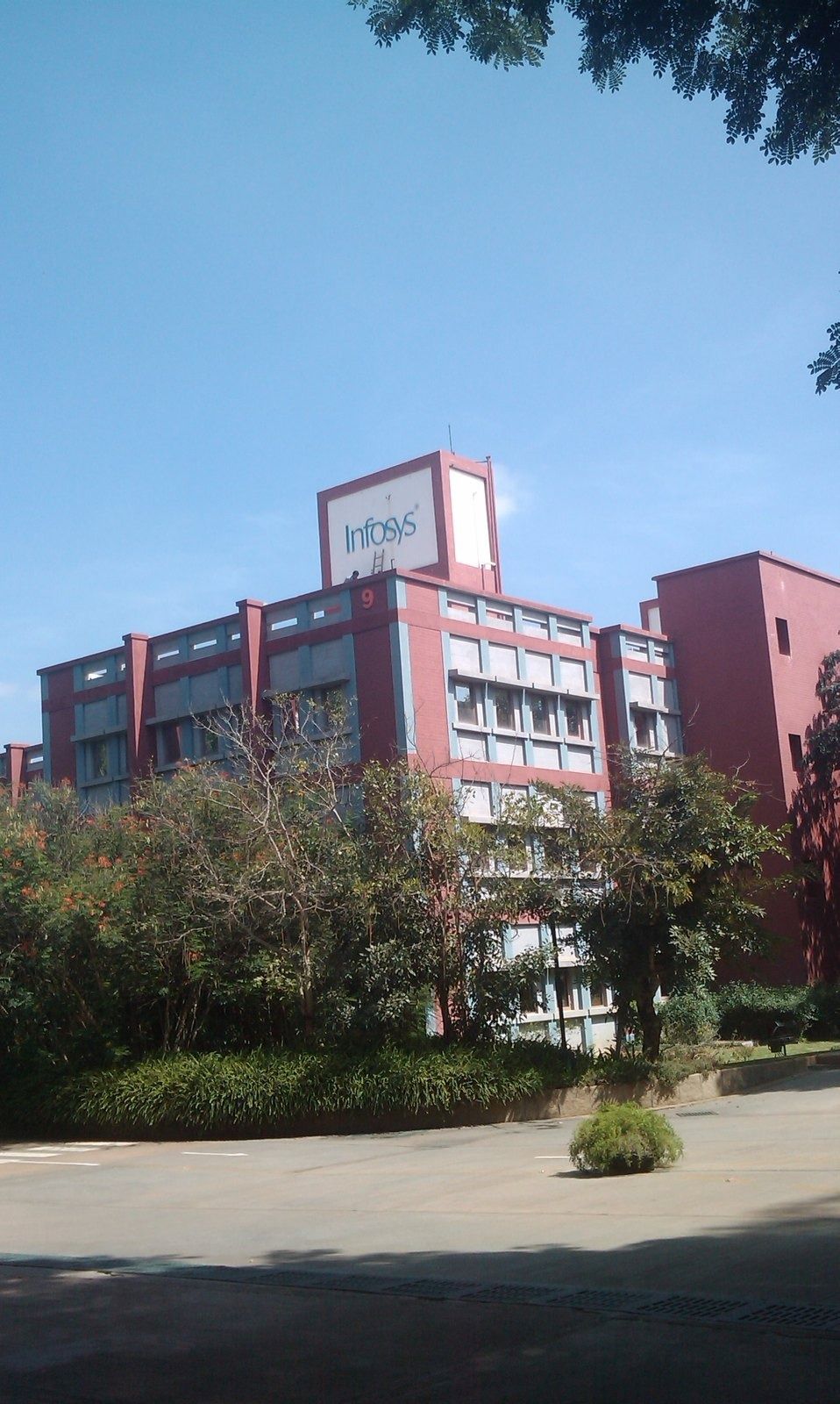 Infosys: Red brick multi-storey building behind trees