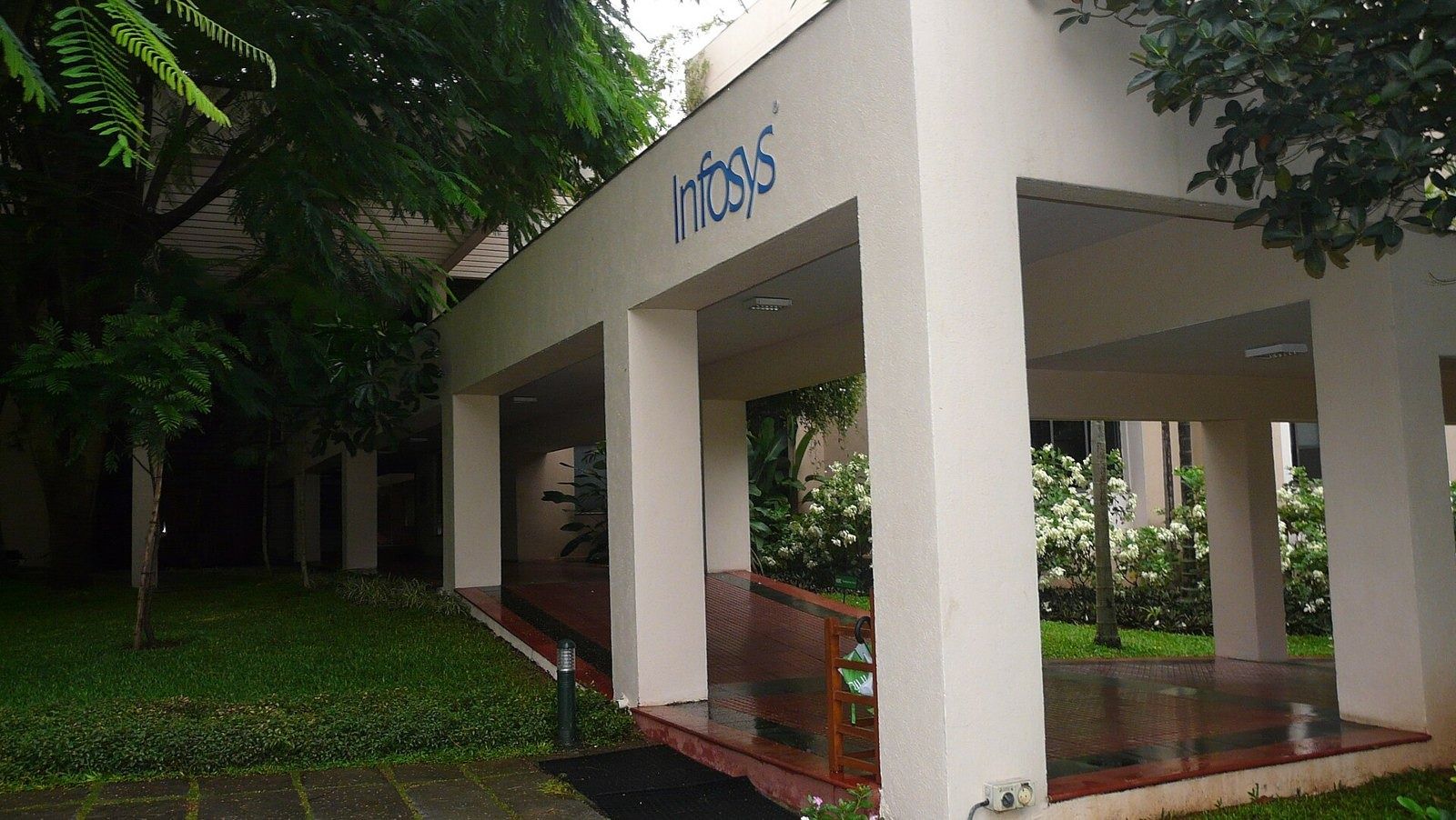 Infosys: White portico with the company name beside garden plants
