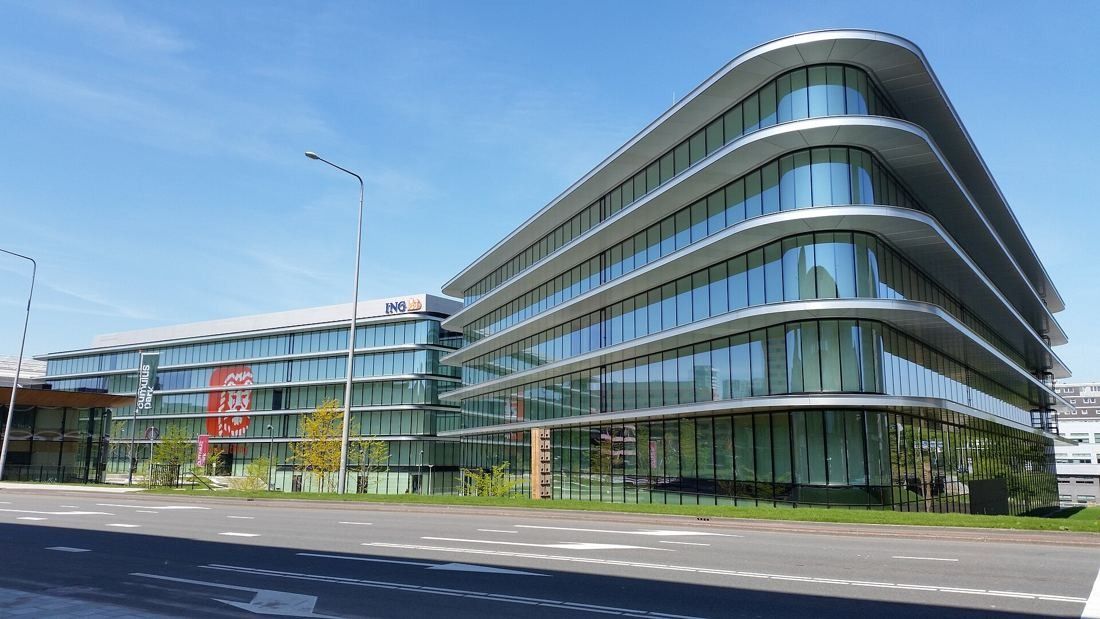 ING Group: Curved corner of a glass office building with white horizontal bands beside a road