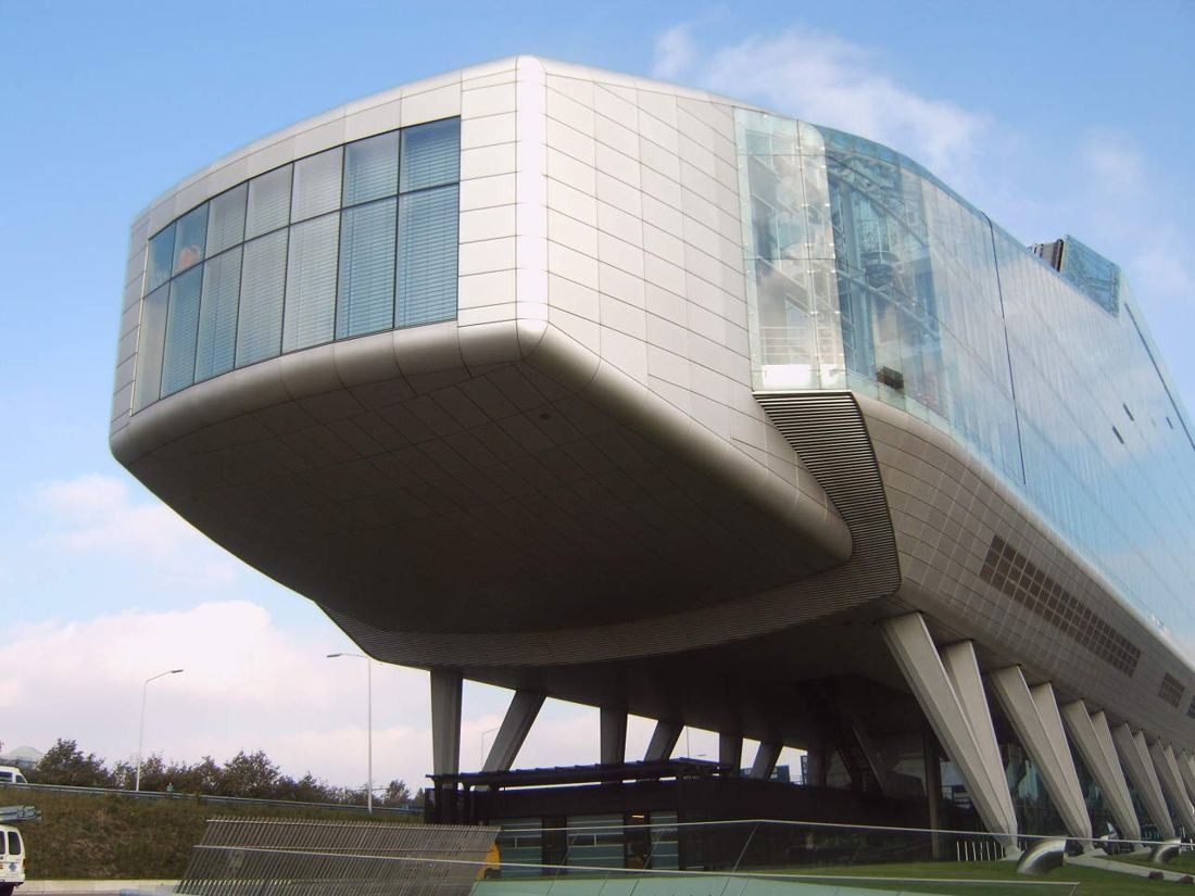 Glass-and-aluminium building raised on slanted stilts