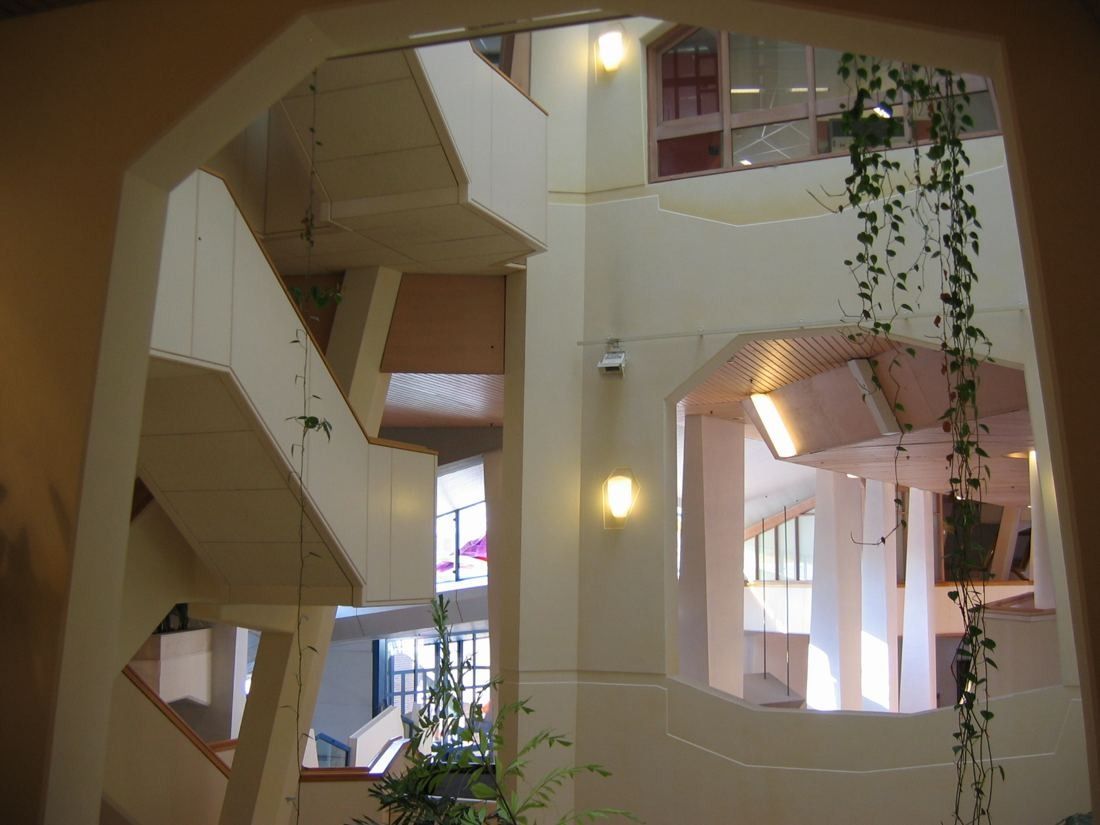 Interior atrium with angled white walls, stairs and hanging plants