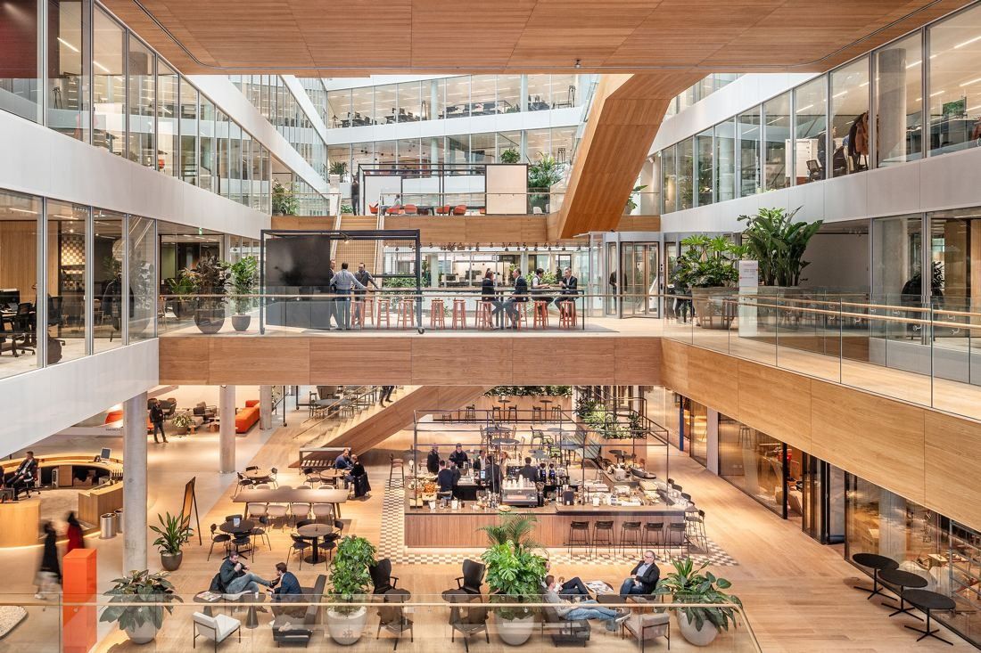 ING Group: Multi-storey atrium with wooden platforms and stairs above a busy ground-floor café area