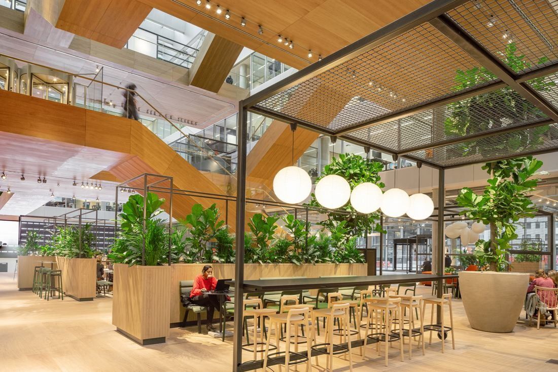 ING Group: Steel-framed pavilion with planters, globe lights and a long bar table under wooden stairs