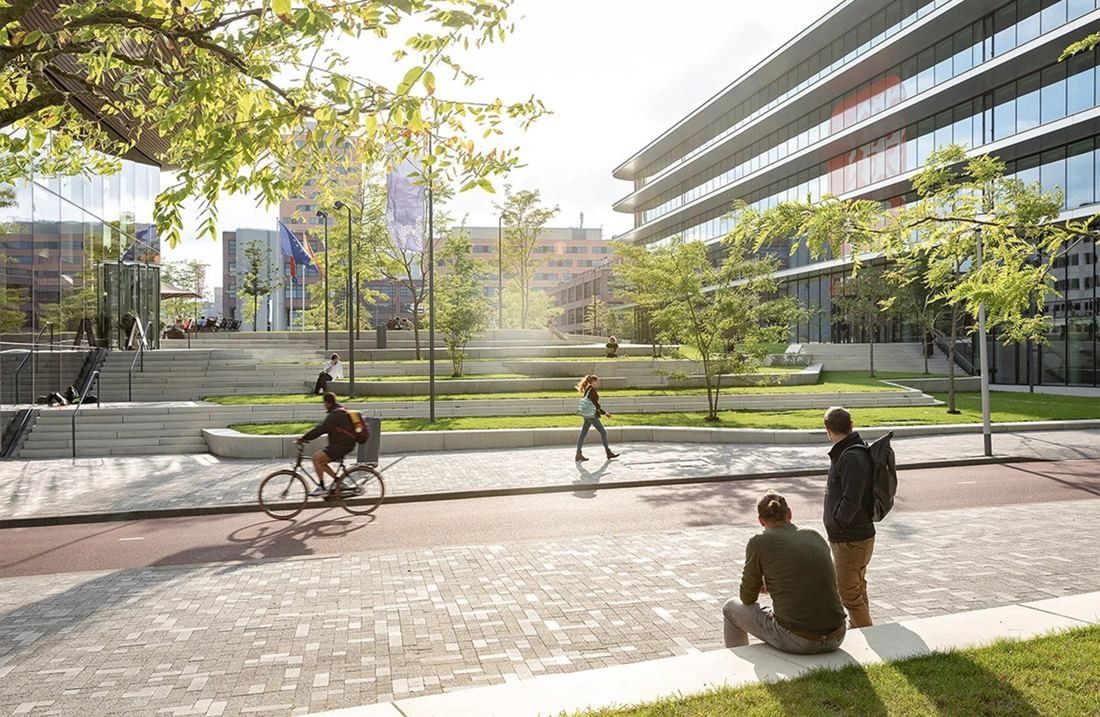 ING Group: Stepped green terraces and paved paths beside a curved glass office building, with a cyclist passing
