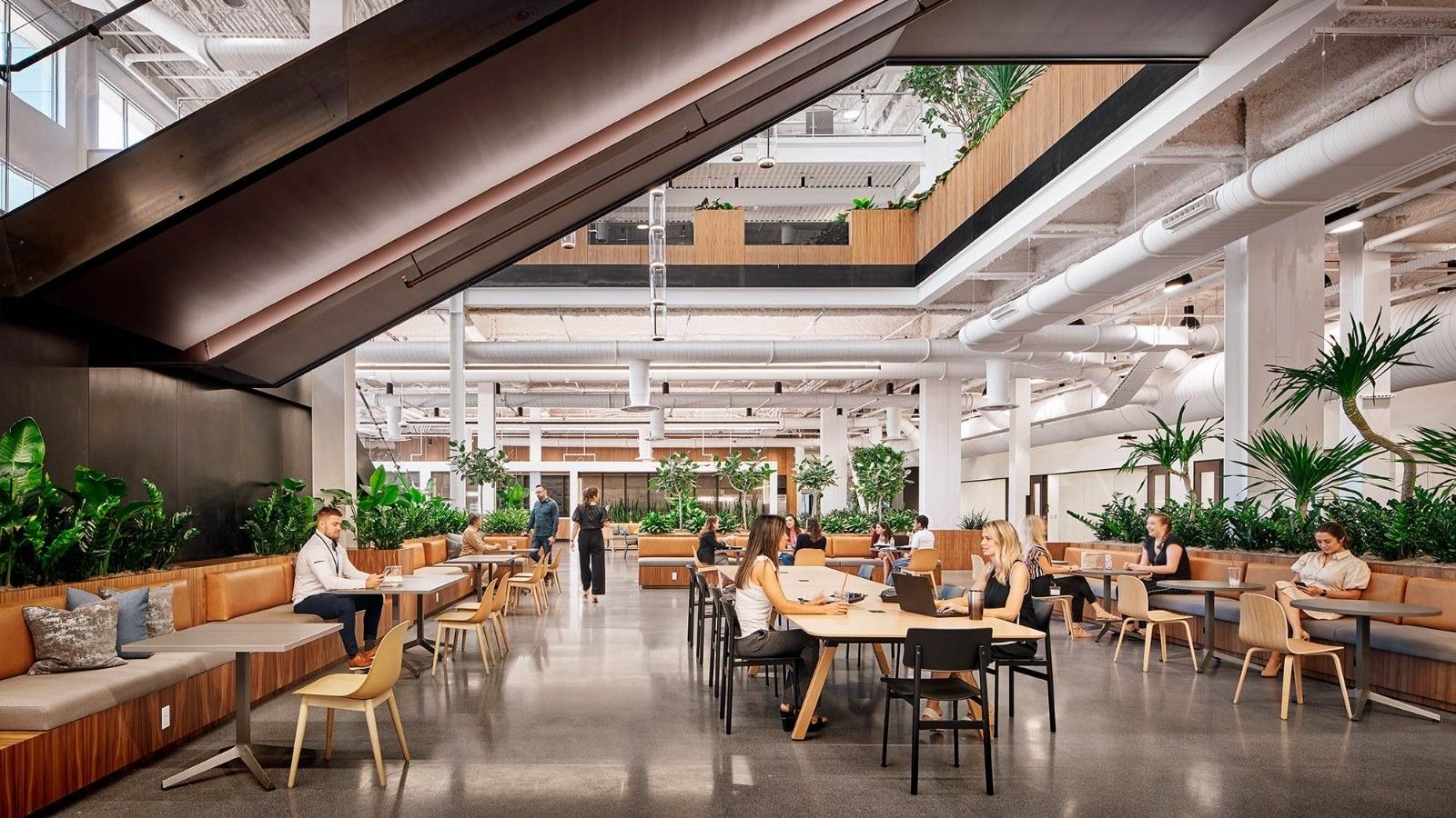 Insight Enterprises: A café area with long tables under an angled stair and hanging plants