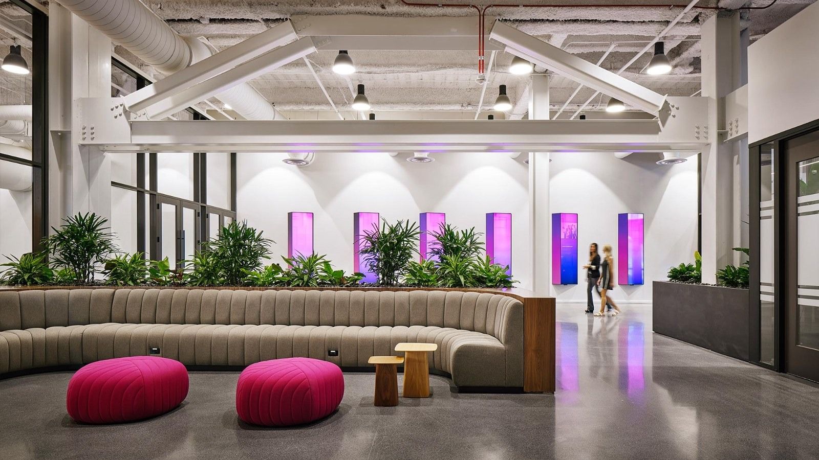 Insight Enterprises: A long curved sofa with pink ottomans and glowing purple panels