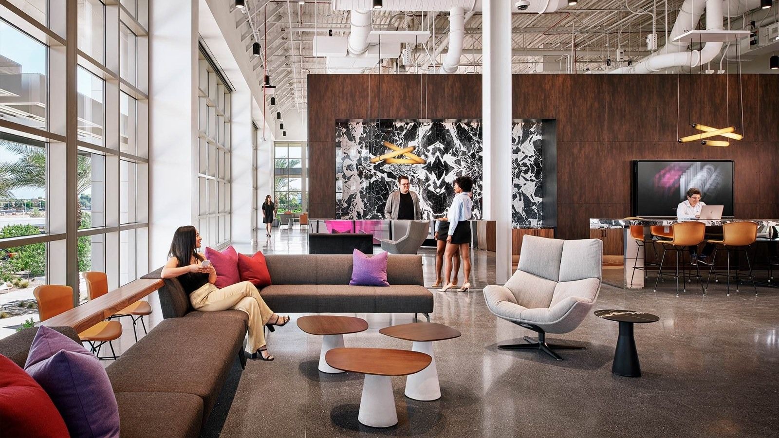 Insight Enterprises: A lounge with a long sofa and white swivel chairs in front of a black-and-white art wall