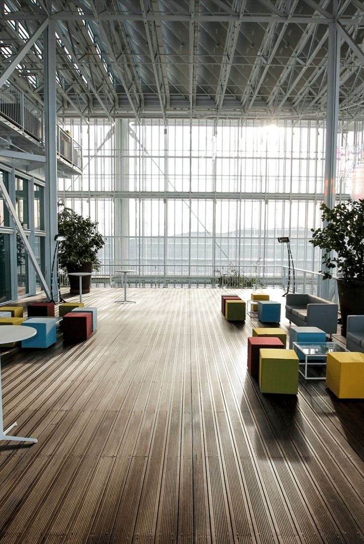 Intesa Sanpaolo: Colourful low seating on a wooden floor in front of a tall glass wall