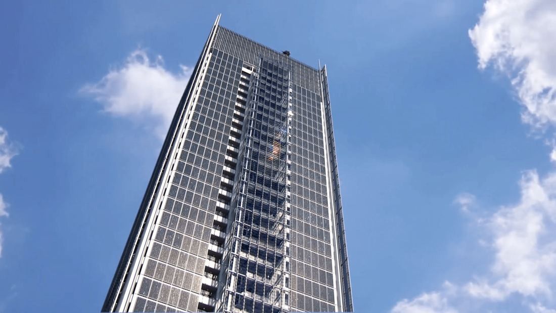 Intesa Sanpaolo: Looking up at the tower's glass facade against a blue sky with clouds