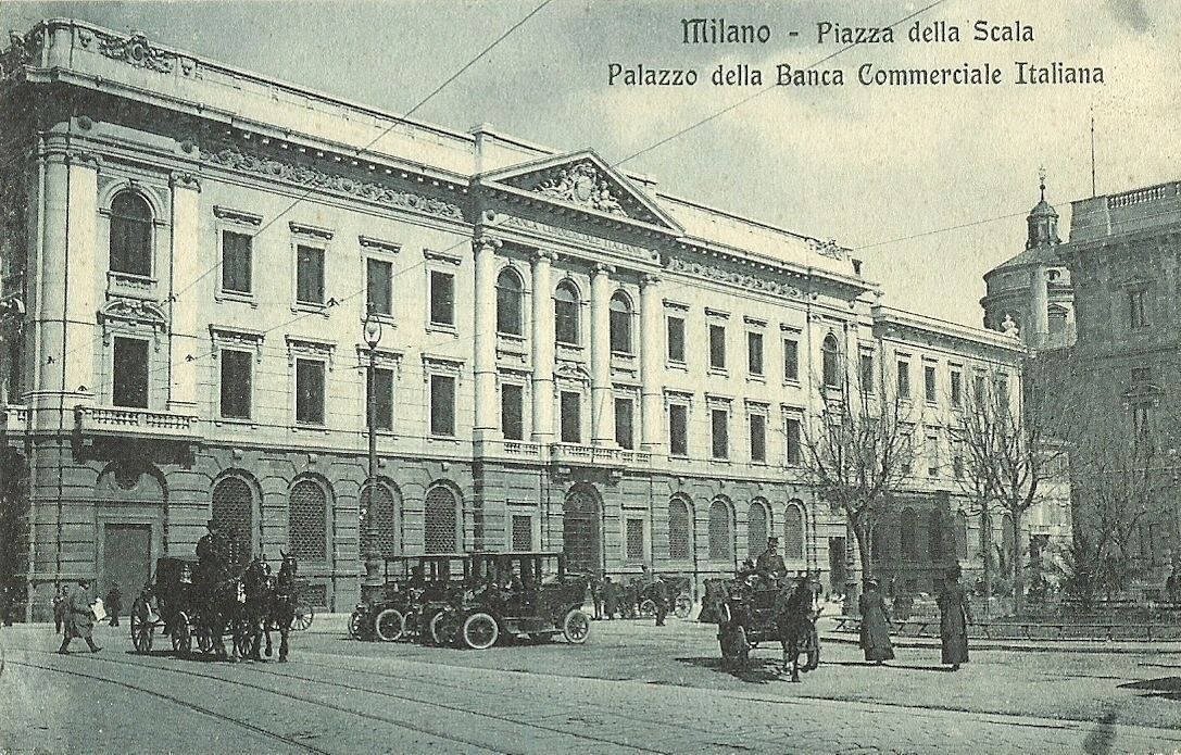Old postcard of a large stone palazzo on a square with horse carriages and early cars
