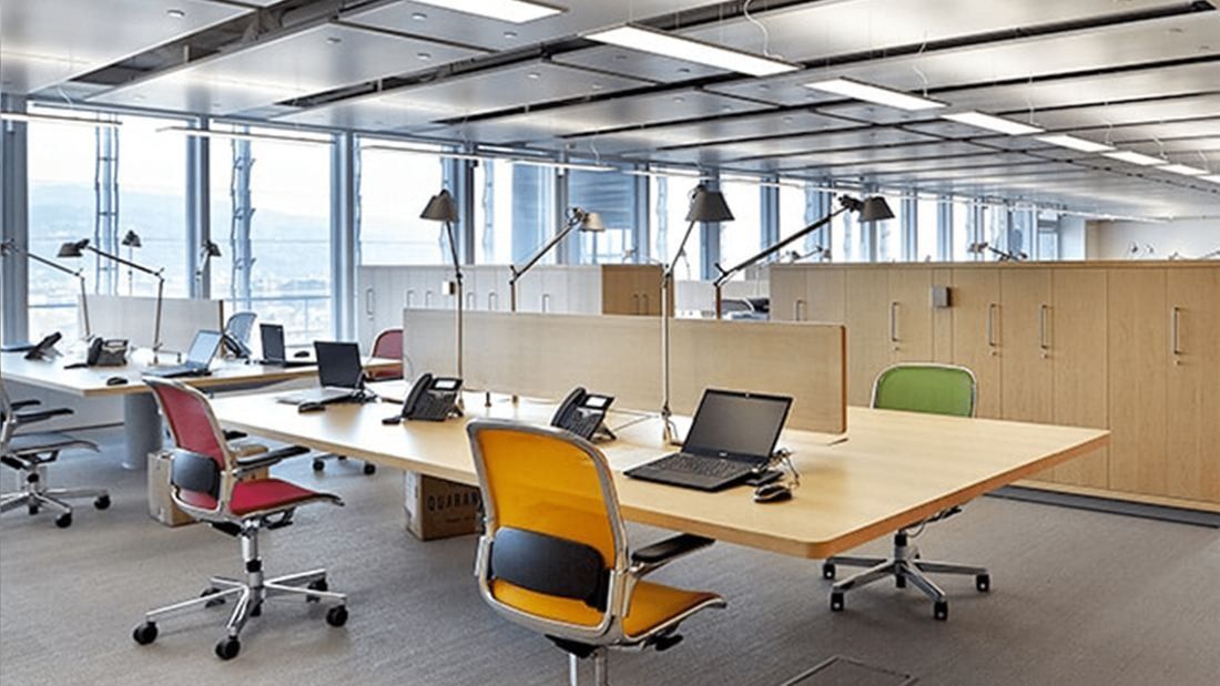 Intesa Sanpaolo: Shared desks with colourful chairs and laptops in an open-plan office