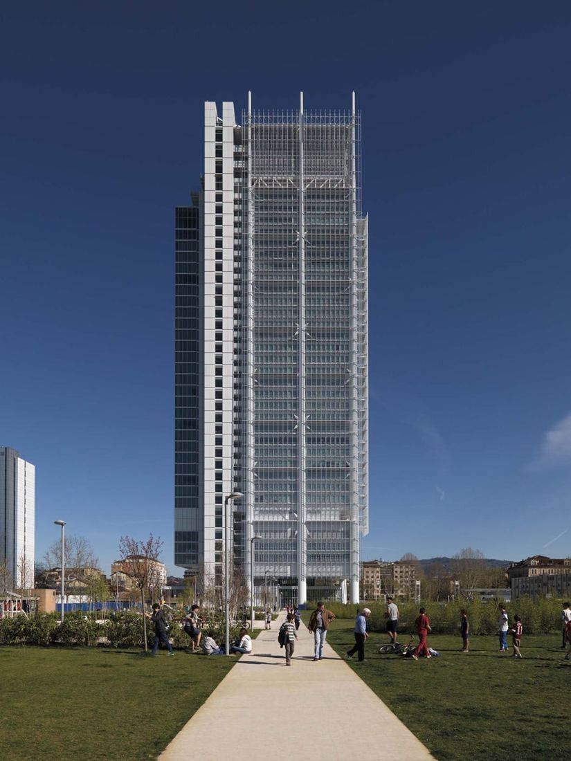 Intesa Sanpaolo: The full height of the tower seen from a path across a lawn under a deep blue sky