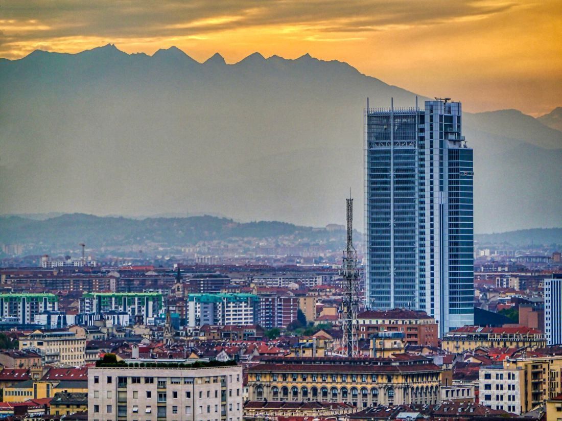 Intesa Sanpaolo: The tower silhouetted against an orange sky and mountain ridge