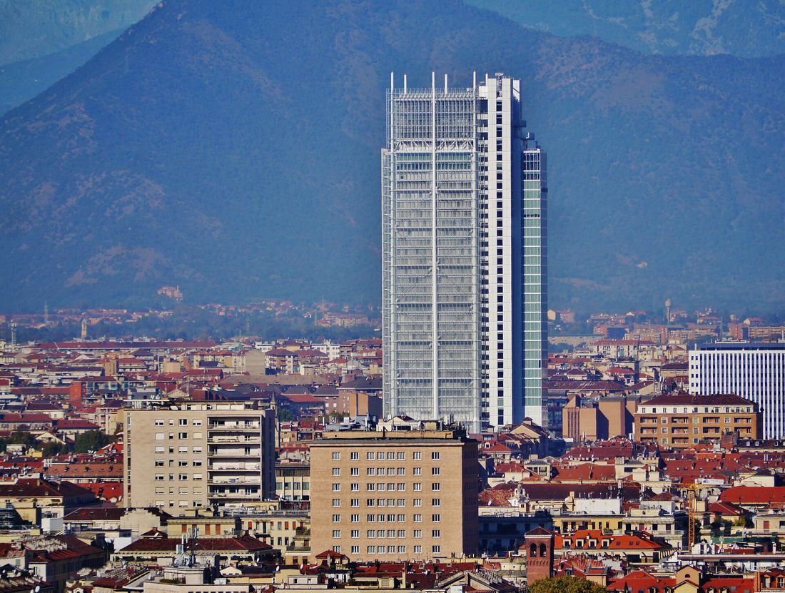 Intesa Sanpaolo: The white tower in front of mountains, seen above Turin's rooftops