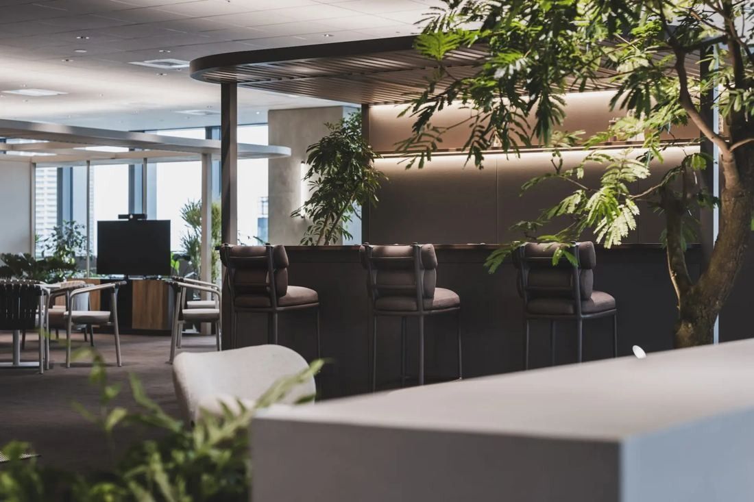 ITOKI: Bar counter and lounge chairs under dark ceilings with trees and city windows