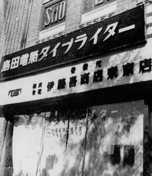 Black-and-white photo of a shopfront with large signboards