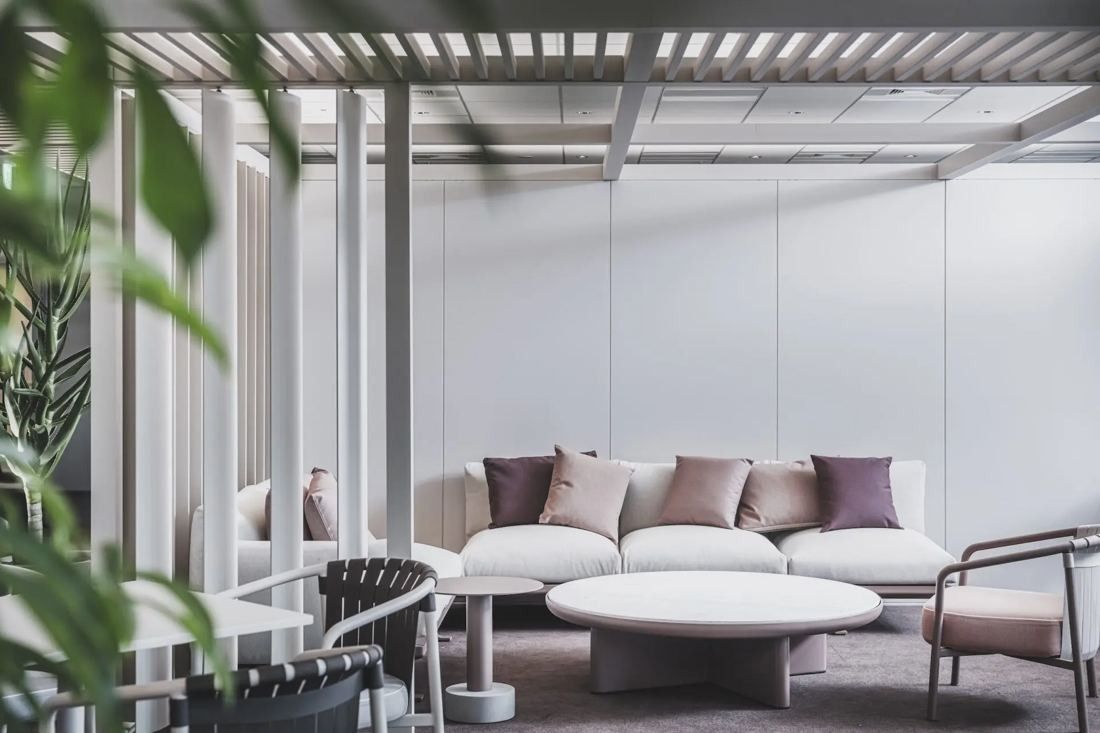 ITOKI: Bright lounge with a sofa and round coffee table under a slatted canopy