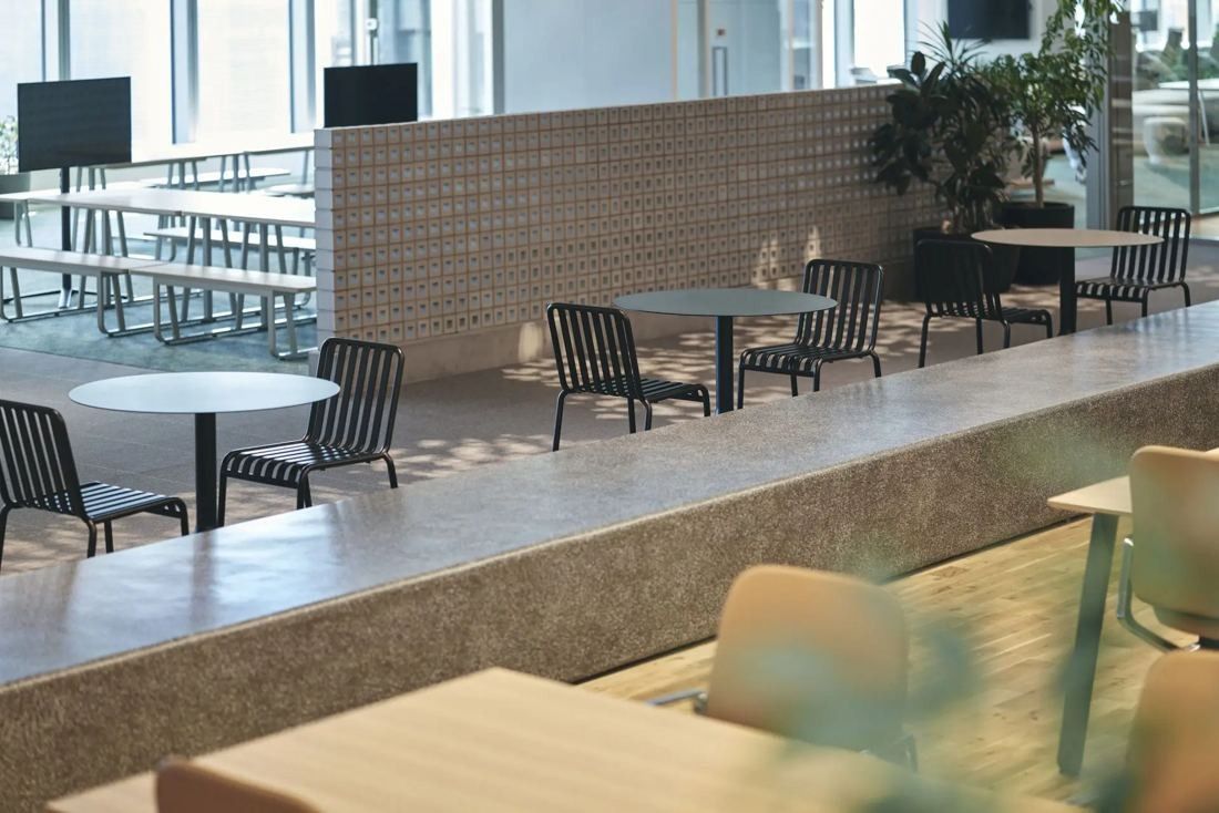 ITOKI: Café-style tables and chairs beside a perforated partition