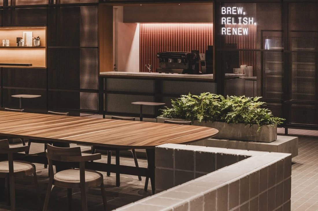 ITOKI: Coffee bar with red fluted wall and BREW, RELISH, RENEW sign, long table in front
