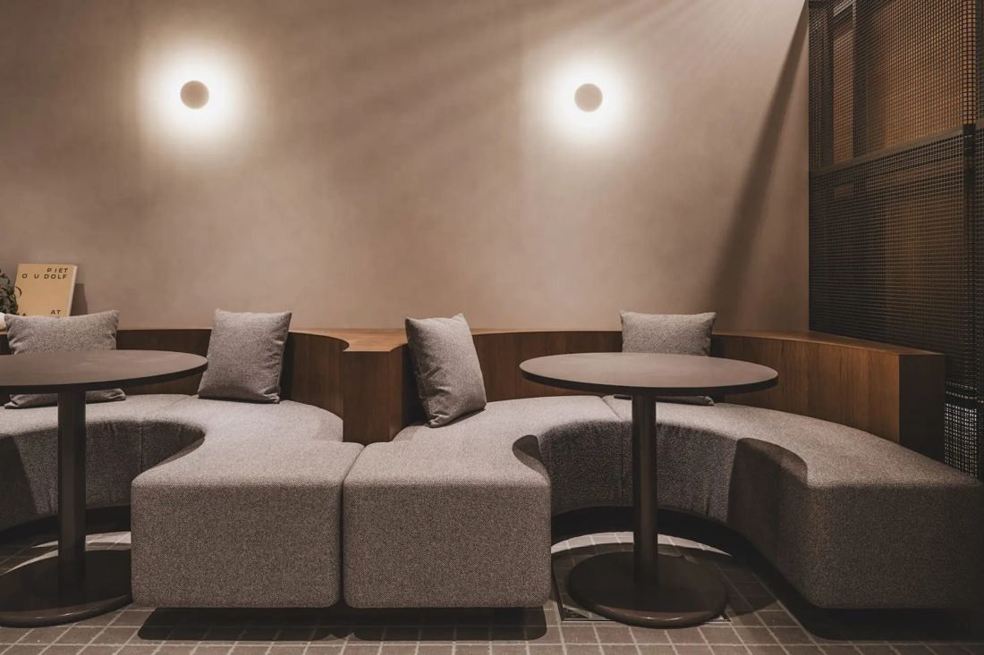 ITOKI: Curved upholstered booth seating with round tables and wall lights
