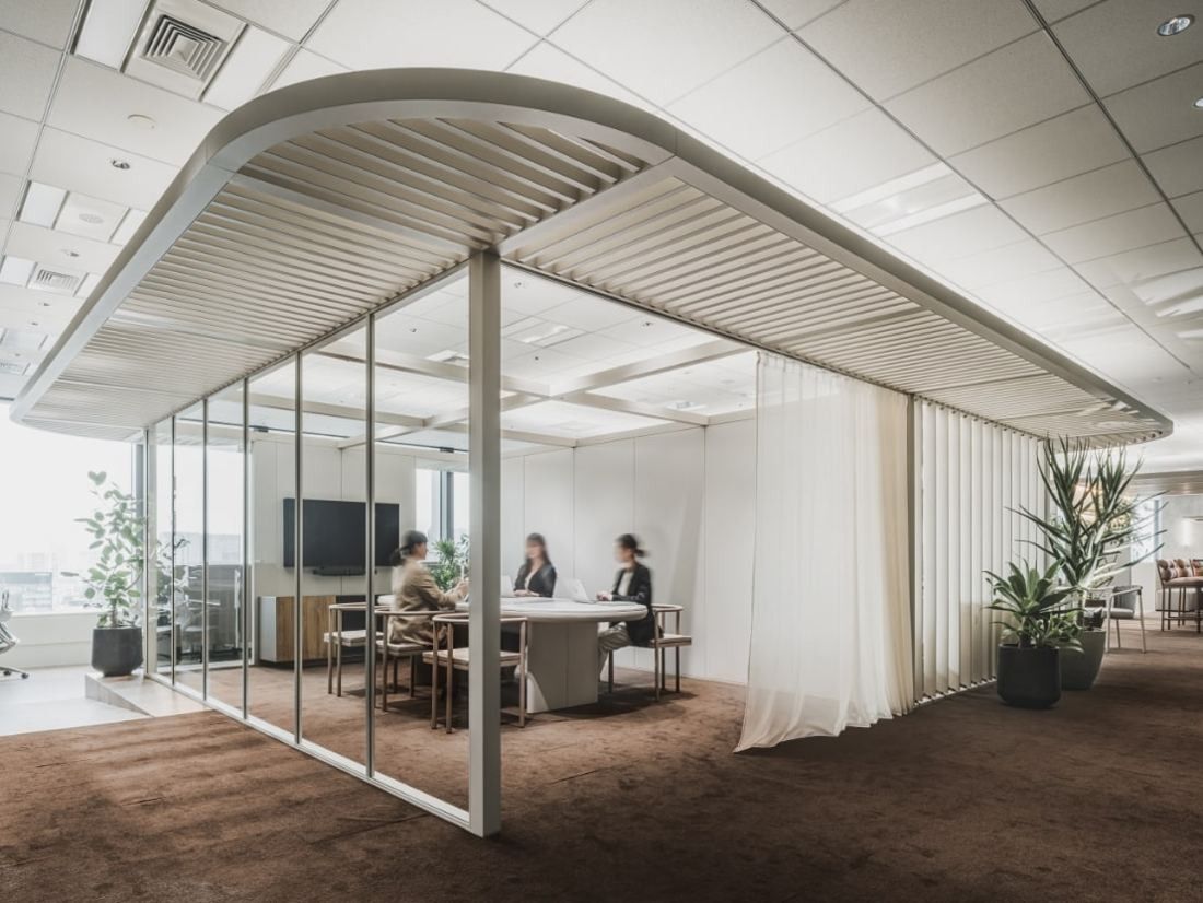 ITOKI: Glass meeting room under a curved slatted canopy with curtains