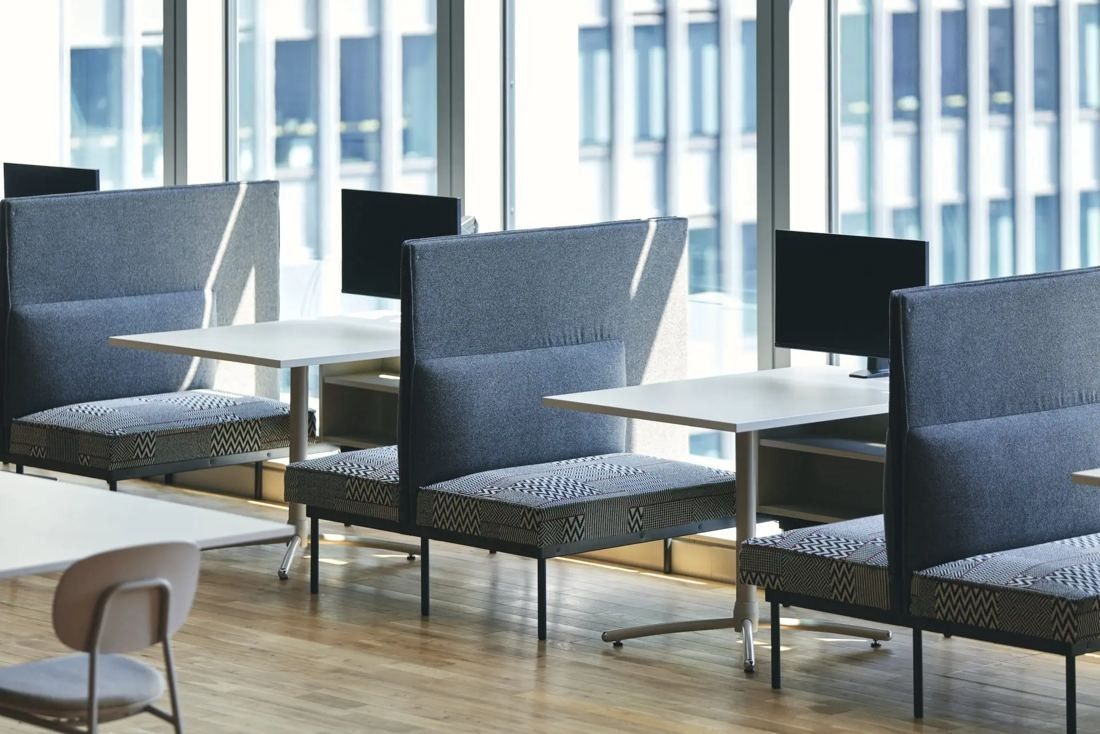 ITOKI: High-backed booth seats with monitors along a window