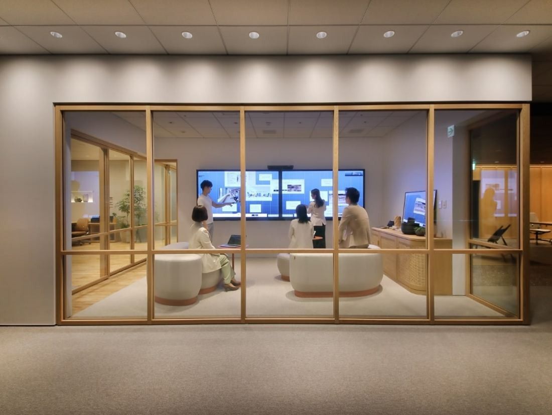 ITOKI: Meeting room behind a wooden-framed glass wall with large screens