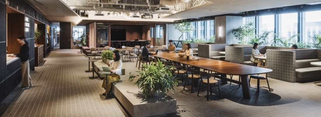 ITOKI: Multi-purpose area with a long wooden table, booths and plants